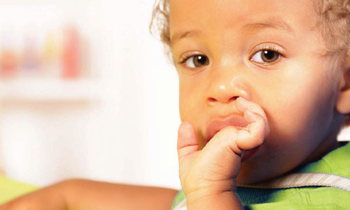 Photo of an african-american child with his hand in his mouth.