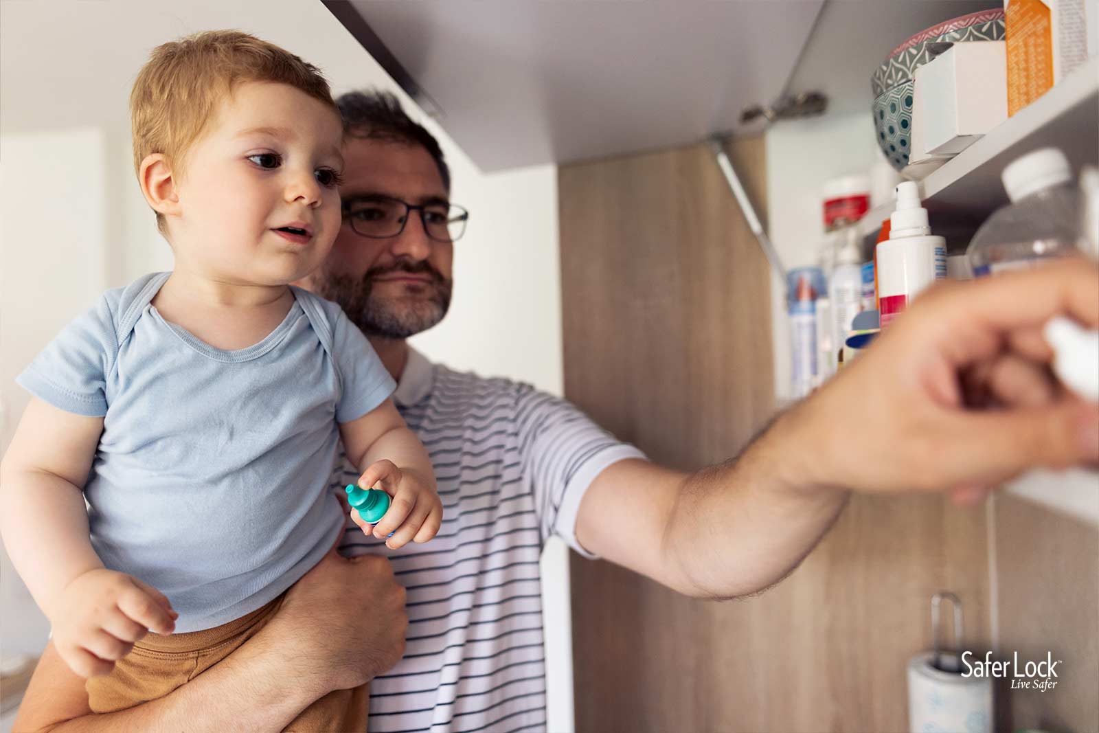 A man holding a toddler while looking at prescription medications in a cabinet.