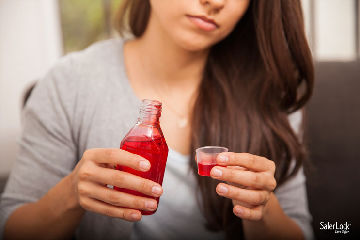 A woman holds a dose of cough syrup.