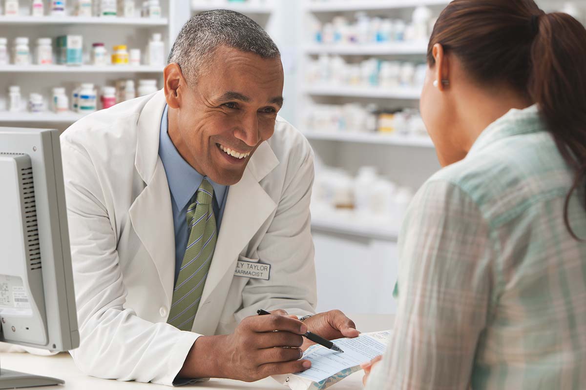Image of friendly pharmacist explaining to a patient how Western Health Advantage offers Gatekeeper Innovation Inc.'s Rx Locking Cap as a covered benefit to its members. Learn more about this exciting new benefit for WHA members.