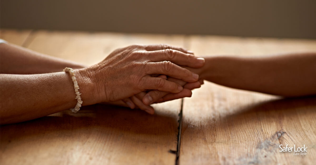 A close-up of two hands clasping another’s hand in support.